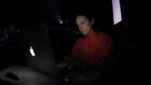 Zia Anger sits in a darkened theater, looking at a laptop, which lights up her face.