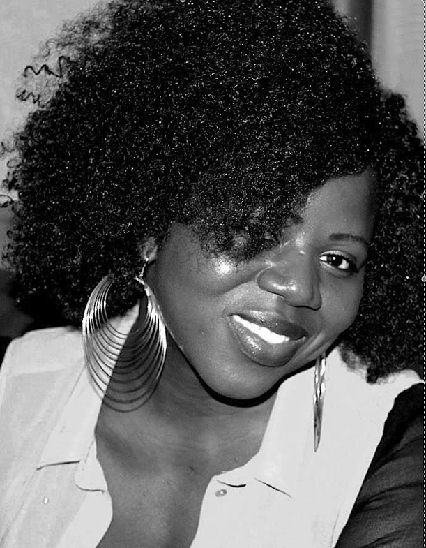 The image is a black and white portrait of filmmaker Eléonore Yameogo. She is a Burkinabe woman with big, black curly hair. Her hair covers one part of her face, but she is facing the camera, smiling.