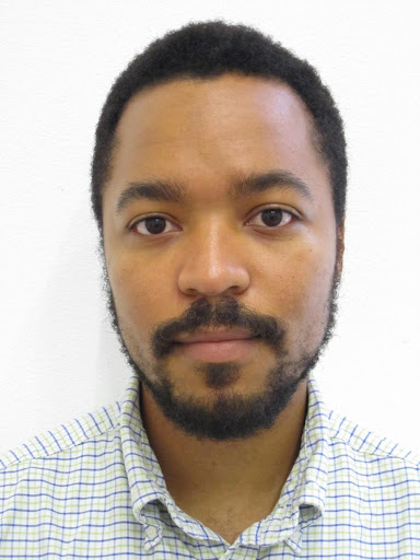 The image is a portrait of the filmmaker Morgan Quaintance. He is a Black man with black hair and a black goatee beard. He is staring directly at the camera calmly.